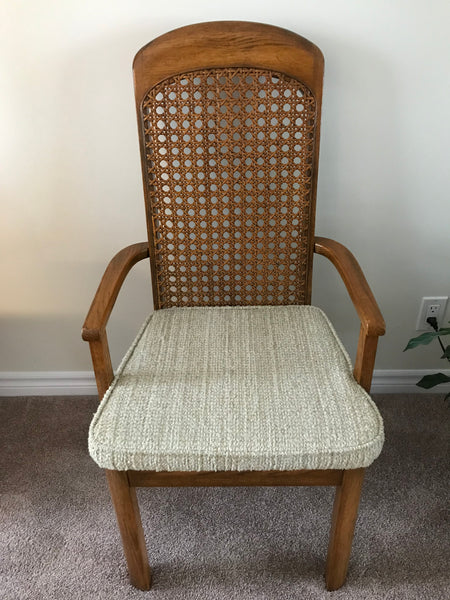 Dining arm chair, wood finish with woven cane inlay and padded cushion.