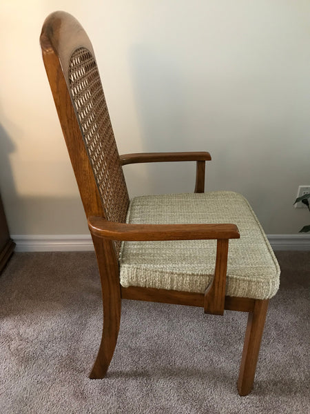 Dining arm chair, wood finish with woven cane inlay and padded cushion.